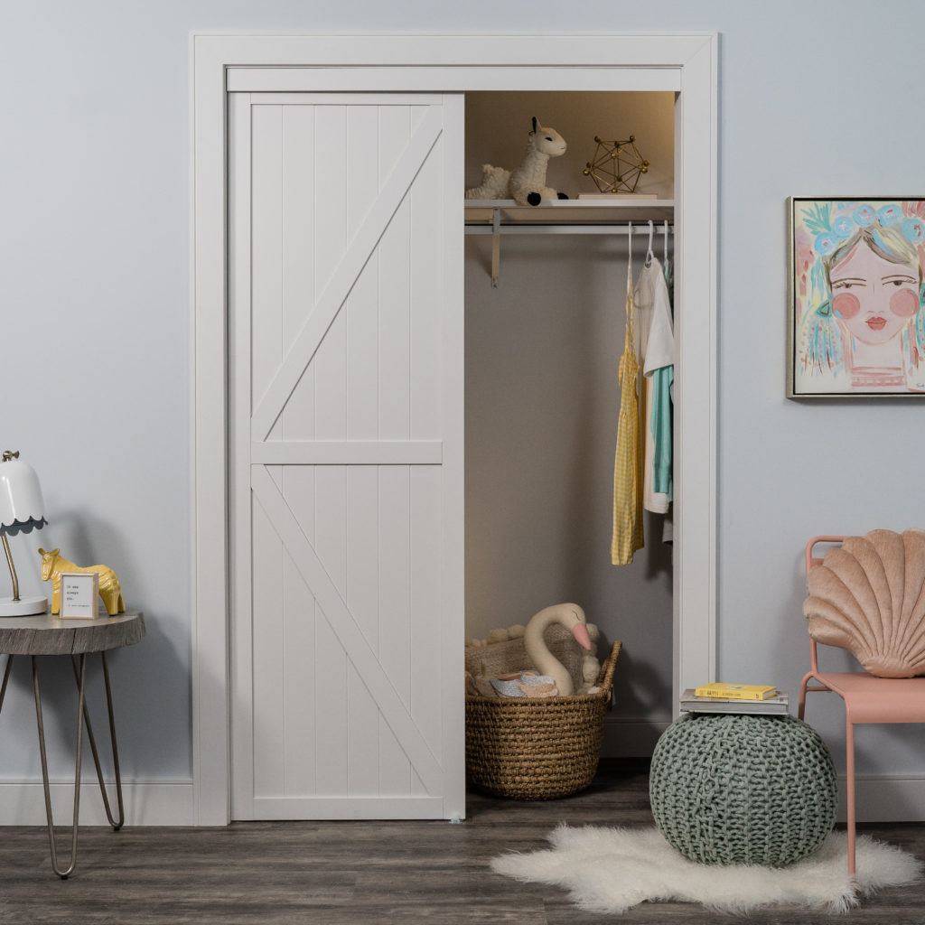 Trident Double-K Design Bypass Closet Door White K Design Bypass Closet Door in a childrens room with pastel toys in closet.